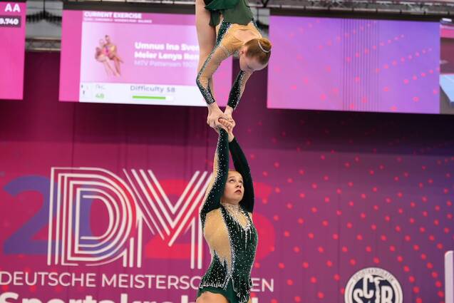 Zwei Akrobatinnen f&uuml;hren eine Hebefigur auf einer Gymnastikmatte w&auml;hrend der Deutschen Meisterschaften durch.