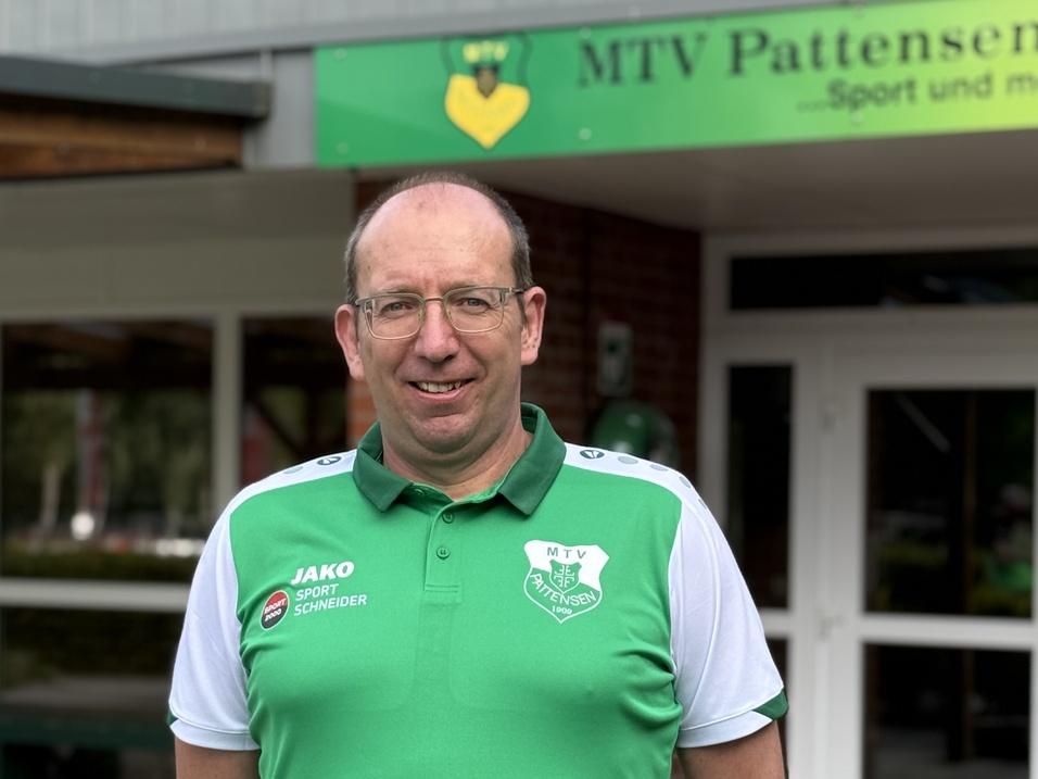 Mann in grün-weißer Sportbekleidung steht vor dem Eingangsbereich des MTV Pattensen.